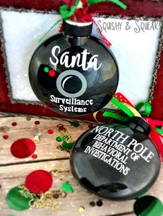 two christmas ornaments with santa's surveillance systems written on the front and back side