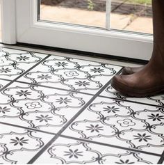 a close up of a person's feet on a tile floor near a door