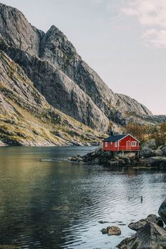 a red house sitting on top of a rocky shore