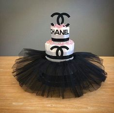 a chanel cake with black tulle and pink icing on top sits on a table