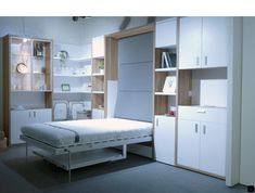 a white bed sitting inside of a bedroom next to a book shelf and cabinets on either side of the bed