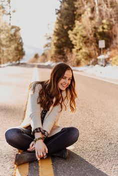 a woman is sitting on the road smiling