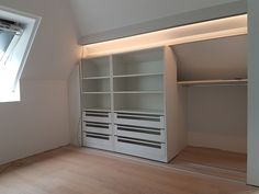 an empty room with white shelves and drawers