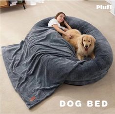 a woman laying on top of a dog bed with a large brown dog sitting next to her