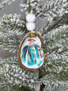 a christmas ornament hanging from the top of a tree with snow on it