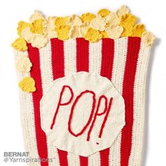 a knitted popcorn bag with the word pop written in red and white yarn on it