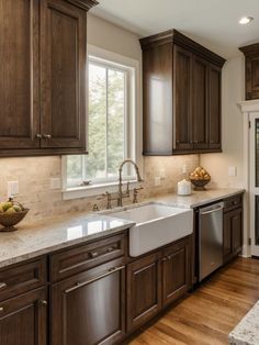 a kitchen with wooden cabinets and marble counter tops, along with a stainless steel dishwasher