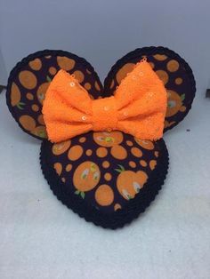 a close up of a mickey mouse head with an orange bow