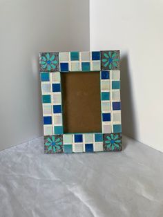 a small blue and white frame sitting on top of a table next to a wall