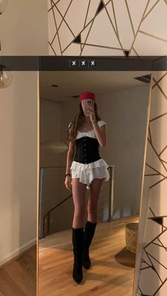 a woman taking a selfie in front of a mirror wearing a short skirt and black boots