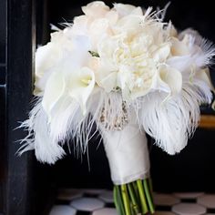 a bridal bouquet with white flowers and feathers