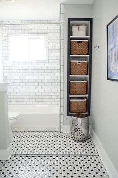 a white bathroom with black and white tile flooring next to a tub filled with wicker baskets