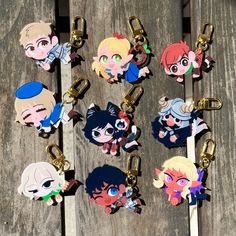 several anime key chains are shown on a wooden surface with clippings attached to them