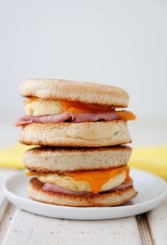 a stack of sandwiches sitting on top of a white plate next to a yellow banana