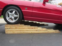 a red sports car is parked on some wooden steps