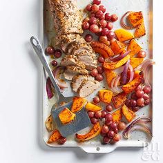 a tray with meat, fruit and vegetables on it next to a cutting board filled with grapes