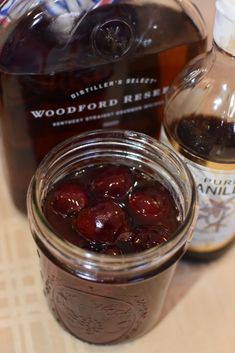 a jar filled with cherries next to a bottle of woodford reserve