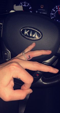 a person's hand on the steering wheel of a car with their fingers in the air