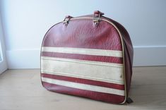 a red and white suitcase sitting on top of a wooden floor