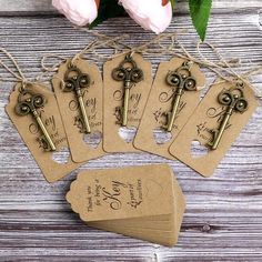 six key tags with the names and date on them are sitting next to some flowers