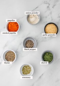 the spices are labeled in small bowls on a marble countertop with labels describing them