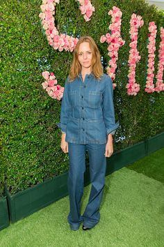 a woman standing in front of a flower wall