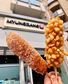 a person holding up a fried food item in front of a store