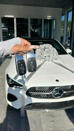 a person holding two keys in front of a white car