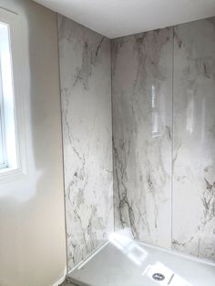 a bath tub sitting next to a window in a room with marble walls and floors