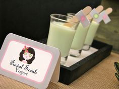 two glasses of green liquid sitting on top of a table next to a sign that says, facial scrub yogurt