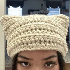 a close up of a person wearing a knitted hat with cat ears on top