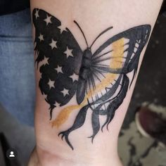 a woman's arm with a butterfly tattoo on it and an american flag in the background