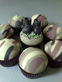 six cupcakes with camouflage print frosting and black shoes on top are arranged in a circle