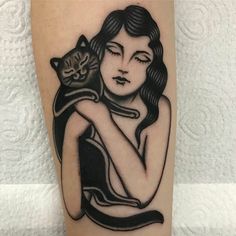 a woman with a cat tattoo on her arm is holding it up to her chest