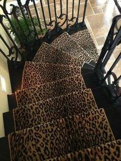 a leopard print rug on the bottom of a stair case next to a black hand rail