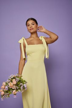 a woman in a yellow dress holding a bouquet