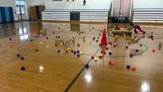 an indoor gym with balls scattered all over the floor