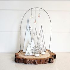 a wooden table topped with metal mountains on top of a piece of driftwood next to a candle holder