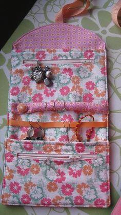 a pink and orange flowered purse sitting on top of a table next to ribbon