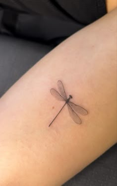 a small dragonfly tattoo on the arm