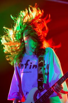 a man with long hair playing an electric guitar