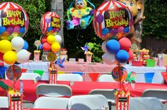 an outdoor birthday party set up with balloons, candy bars and clowns on the tables