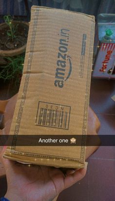 someone holding up a box with the amazon logo on it