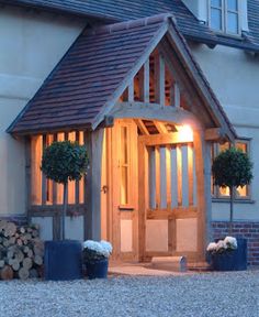 the front entrance to a house lit up at night with lights on and potted plants outside