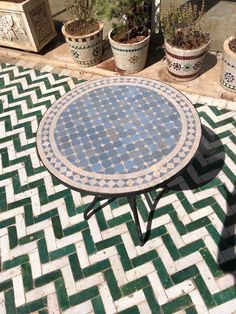 a table sitting on top of a tiled floor next to potted plants