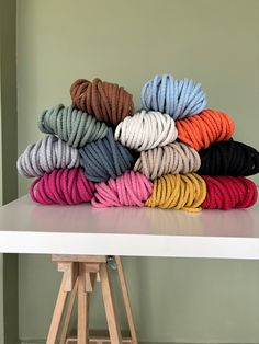 several skeins of colored yarn sitting on top of a white table in front of a green wall