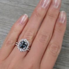 a woman's hand holding an engagement ring with a black and white diamond center