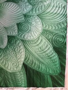 a close up view of a quilt with green leaves and swirls in the center