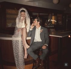 a man sitting next to a woman in a wedding dress at a bar with her legs crossed