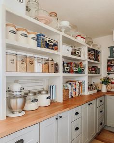 a kitchen filled with lots of white cupboards and wooden counter top space next to an oven